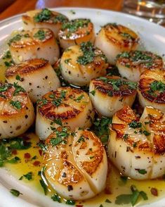 some scallops are on a white plate with sauce and parsley around them