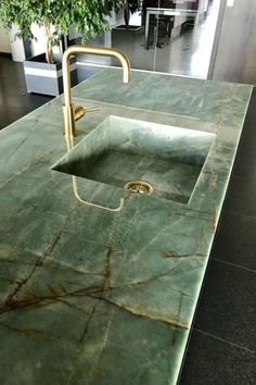 a green marble counter top with a sink and faucet in the middle,