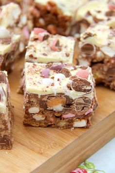 several pieces of dessert sitting on top of a wooden cutting board