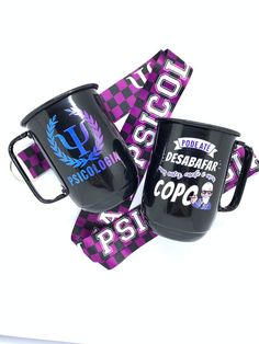 two black coffee mugs sitting next to each other on top of purple and white ribbons