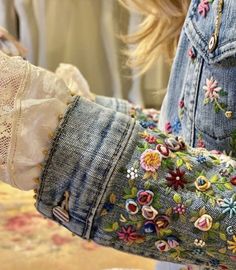 a close up of a person wearing a jean jacket with flowers on it's sleeves