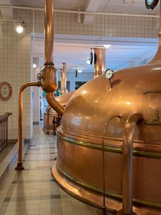 there is a large copper pot in the middle of a room that has many pipes