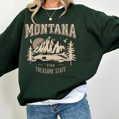 "Montana Sweatshirt, Montana Vacation Sweater, Trendy Sweatshirt, Mountain Mama Gift: This cozy sweatshirt features a captivating mountain graphic in shades of pink. Crafted for comfort and warmth, this trendy sweatshirt is the perfect blend of fashion and functionality making it your go-to choice for chilly days. Make a statement and showcase your love for Montana's majestic scenery with this unique and stylish sweatshirt. Perfect for yourself or as a thoughtful gift for anyone who appreciates The Treasure State.  🎄🎁 IMPORTANT : CHRISTMAS DELIVERY CUTOFF: ORDER BY DECEMBER 11TH! 🎁🎄 NOTE Mockups are used for demonstration purposes only, and the final product may vary slightly in color & placement. SIZE & FIT: Unisex Heavy Blend™ Crewneck Sweatshirt Design is scaled down on smaller size Trendy Long Sleeve Tops For Outdoor, Trendy Outdoor Sweatshirt With Graphic Print, Trendy Outdoor Graphic Print Sweatshirt, Casual Outdoor Sweater With Letter Print, Outdoor Long Sleeve Graphic Sweater, Trendy Graphic Print Sweatshirt For Outdoor, Casual Winter Hiking Tops, Casual Letter Print Sweater, Fall Hiking Sweatshirt Crew Neck