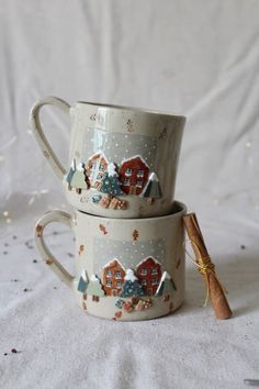 three coffee mugs decorated with houses and trees are stacked on top of each other