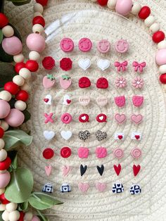 a close up of many different types of buttons on a white surface with red and pink beads