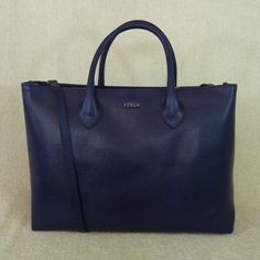 Classic Martha Tote By Furla. This Bag Is Made Of Dark Blue With Purple Hue Saffiano Leather Dimensions: 14" Wide Across X 10.5" Tall Center X 4" Deep. Double Handle 5" Drop. You Can Only Carry It Over The Shoulder If You Have Small Arms. Comes With Long Detachable Shoulder Strap Center Zipper Bonus Compartment 1 Slip Pockets And 1 Zipper Pocket Furla Logo Fabric Lining. Silver Tone Metalware. Comes Complete With Dustbag And Care Card Blue Saffiano Leather Bag For Formal Occasions, Shopping Bag With Silver-tone Hardware In Epsom Leather, Classic Blue Saffiano Leather Bag, Epsom Leather Bags With Silver-tone Hardware For Shopping, Blue Saffiano Leather Evening Bag, Blue Saffiano Leather Top Handle Bag, Saffiano Leather Bag With Silver-tone Hardware For Shopping, Blue Saffiano Leather Bag For Everyday Use, Chic Blue Saffiano Leather Bag