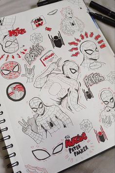 a notebook with spiderman stickers on it and some pens in front of it