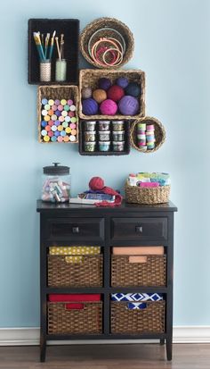 the wall is painted blue and there are baskets on top of the table with craft supplies