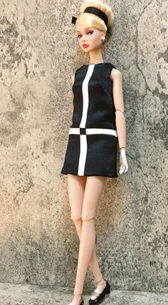 a barbie doll is standing next to a wall