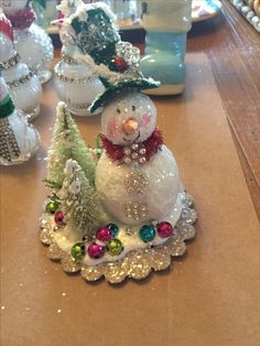 a snowman sitting on top of a table next to other christmas decorations and trees