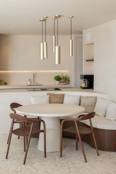 a white table with four chairs around it in the middle of a living room and kitchen area