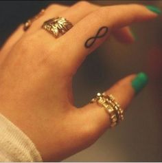 a woman's hand with two different rings on her fingers and one has an arrow tattoo