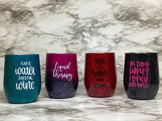 four wine glasses with different sayings are lined up on a marble countertop in front of a marble wall