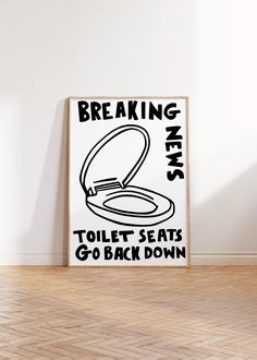 a poster with the words breaking news toilet seats go back down on it in front of a white wall