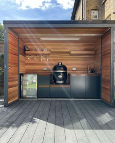 an outdoor kitchen area with wooden walls and flooring on the side of a building