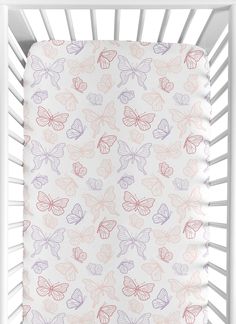 a white crib with pink, purple and orange butterflies on the sheet in front of it