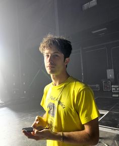 a young man in a yellow shirt holding a cell phone