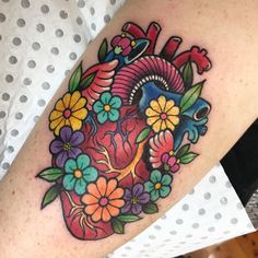 a heart tattoo with flowers and birds on the side of her arm, which is decorated in bright colors