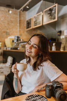 a woman sitting at a table holding a coffee cup