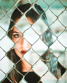 a woman looking through a chain link fence