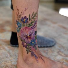 a close up of a person's foot with a flower tattoo on the leg