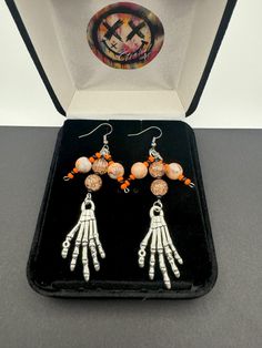 Embrace the spooky season with these Halloween dangling earrings that capture the essence of the holiday perfectly. Adorned with intricately designed skeleton hands and glass beads, each earring tells a whimsical tale of Halloween folklore. The lightweight yet eye-catching design ensures comfort while making a bold statement. Whether you're dressing up for a costume party or simply adding a touch of Halloween spirit to your ensemble, these earrings are the ideal accessory. Let these festive earrings be your playful companion throughout the Halloween season, adding a touch of macabre charm to any outfit. Celebrate the magic of Halloween with these unique, themed earrings that are sure to turn heads and spark conversations wherever you go. Drop Length: 3" Findings: Stainless Steel Tales Of Halloween, Skeleton Earrings, Gothic Earrings, Skeleton Hands, Halloween Accessories, Spirit Halloween, Costume Party, Skeleton, Jewelry Earrings Dangle