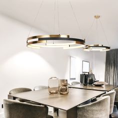 a dining room table with chairs and lights hanging from it's ceiling over it