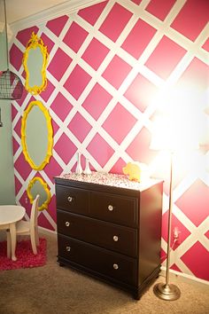 a baby's room decorated in pink and white with yellow accents, including a crib