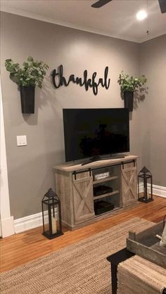 a living room with a large tv and plants on the wall, along with a chandelier