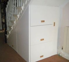 a white refrigerator freezer sitting next to a stair case in a room with carpeted flooring