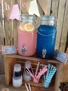 three jars filled with different colored drinks on top of a wooden shelf in front of a fence