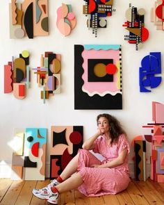 a woman is sitting on the floor in front of some art