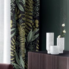 two white vases sitting on top of a wooden cabinet next to a green wall