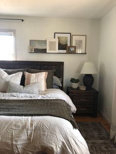 a bed sitting in a bedroom next to a window with pictures on the wall above it