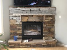 a television mounted above a stone fireplace with a flat screen tv on it's side