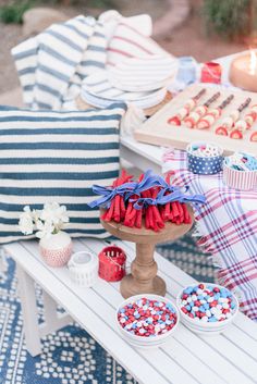 an outdoor picnic table with red, white and blue desserts on it's side