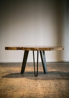 a wooden table sitting on top of a hard wood floor next to a white wall