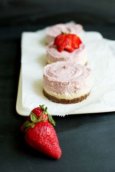 three small desserts with strawberries on a white plate