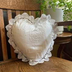 a white heart shaped pillow sitting on top of a wooden chair