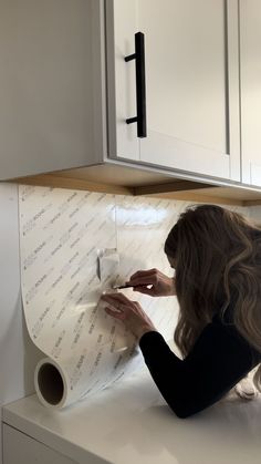 a woman is writing on a piece of paper in the middle of a kitchen counter