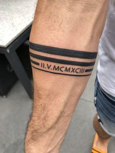 a man with a tattoo on his leg that reads vi moxcilla and is standing next to a table