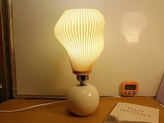 a white lamp sitting on top of a table next to a book