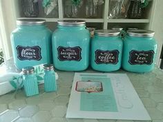 blue mason jars with labels on them are sitting on a counter next to some other items