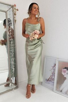 a woman standing in front of a mirror wearing a dress with flowers on the side