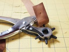 a pair of scissors is sitting on top of a cutting board with some leather trimming around it