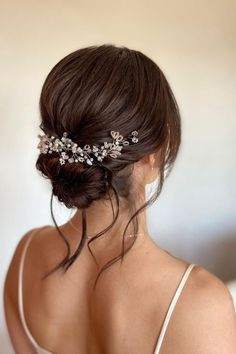 a woman wearing a hair comb with flowers on it's head and her back to the camera