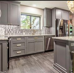 a large kitchen with gray cabinets and marble counter tops is pictured in this image from the front view