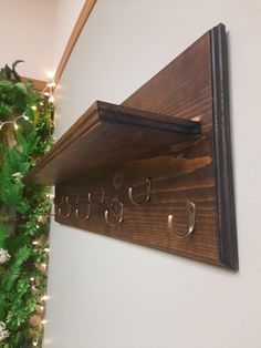 a wooden coat rack with metal hooks on it and christmas lights hanging from the wall behind it