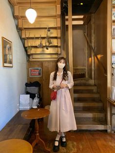 a woman wearing a face mask standing in front of a stairway with tables and chairs