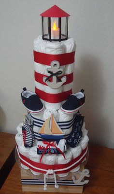 a cake made to look like a lighthouse with nautical items on it and a lit candle in the center